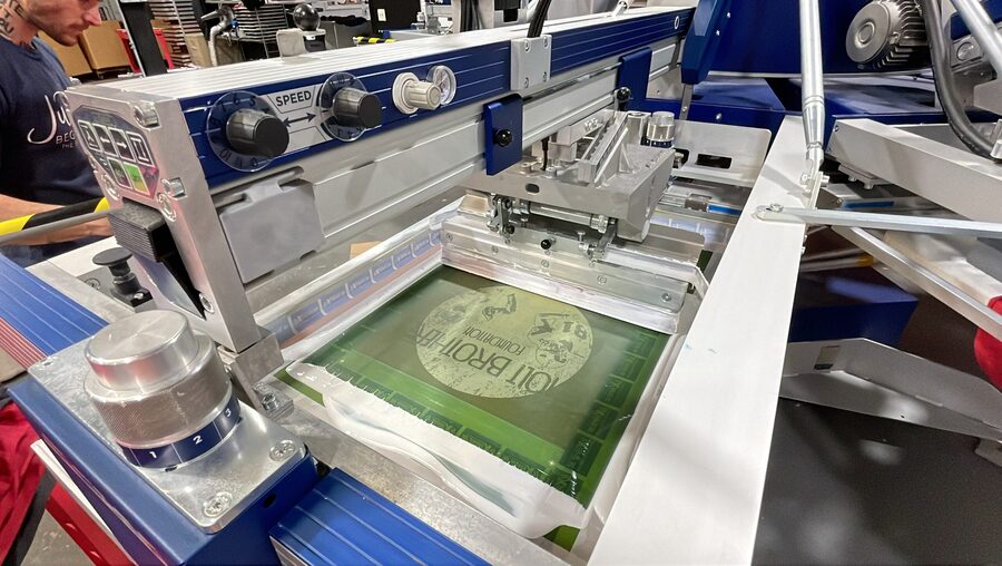 A loaded screen on the press mid-print at BaySix
