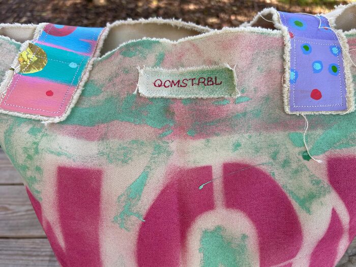 Hand-embroidered QCMSTRBL maker's label stitched into a tote