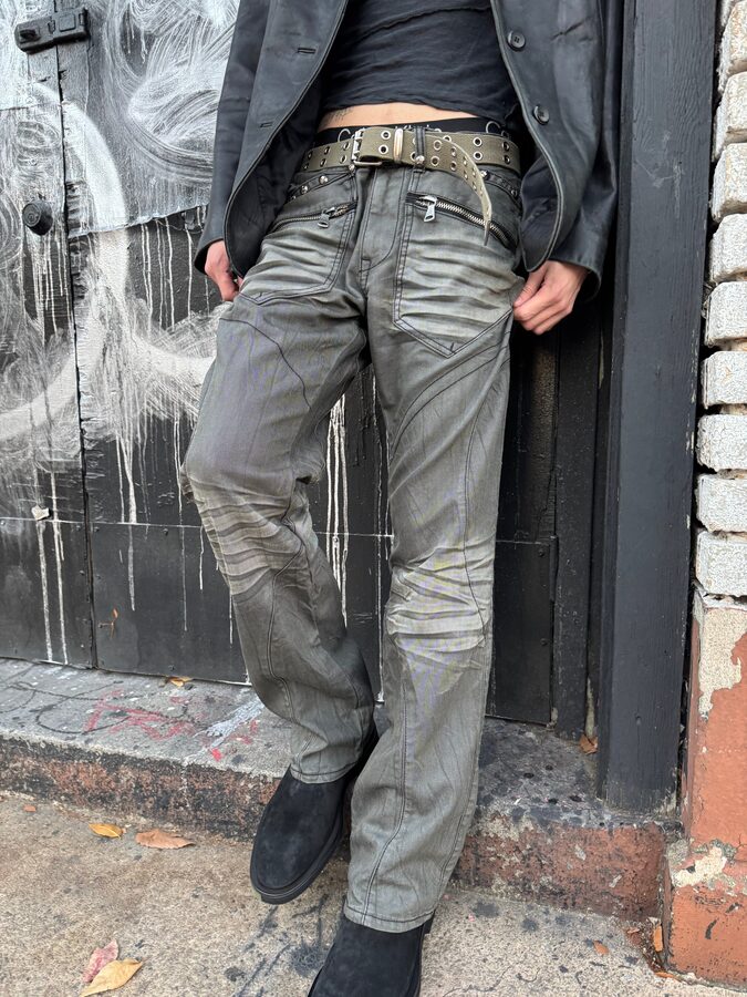 Model in distressed moto jeans and a leather jacket outside a graffitied storefront