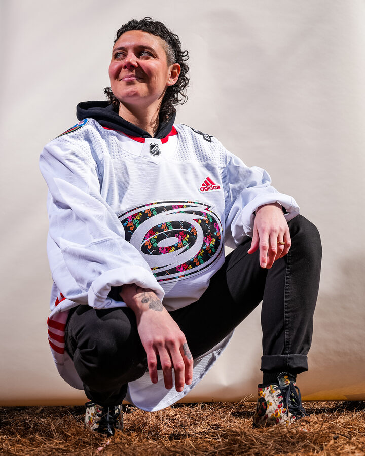 Chelsea Amato wearing the Carolina Hurricanes Pride jersey she designed, with the hurricane warning crest filled with embroidered flowers